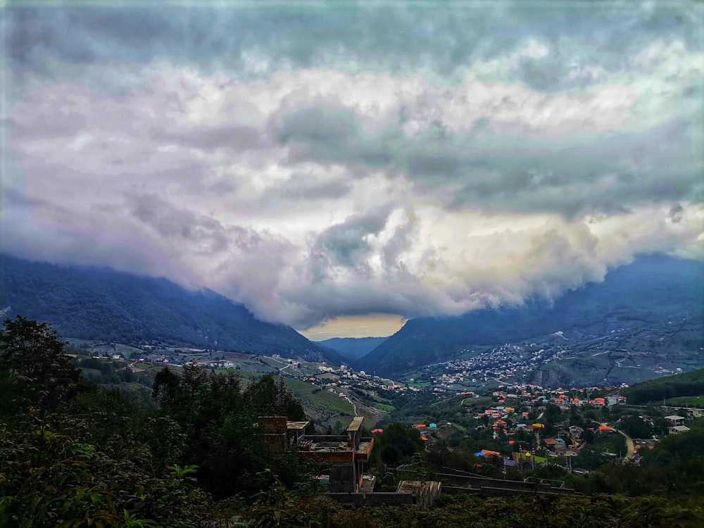 a scenic view of a town and mountains under a cloudy sky