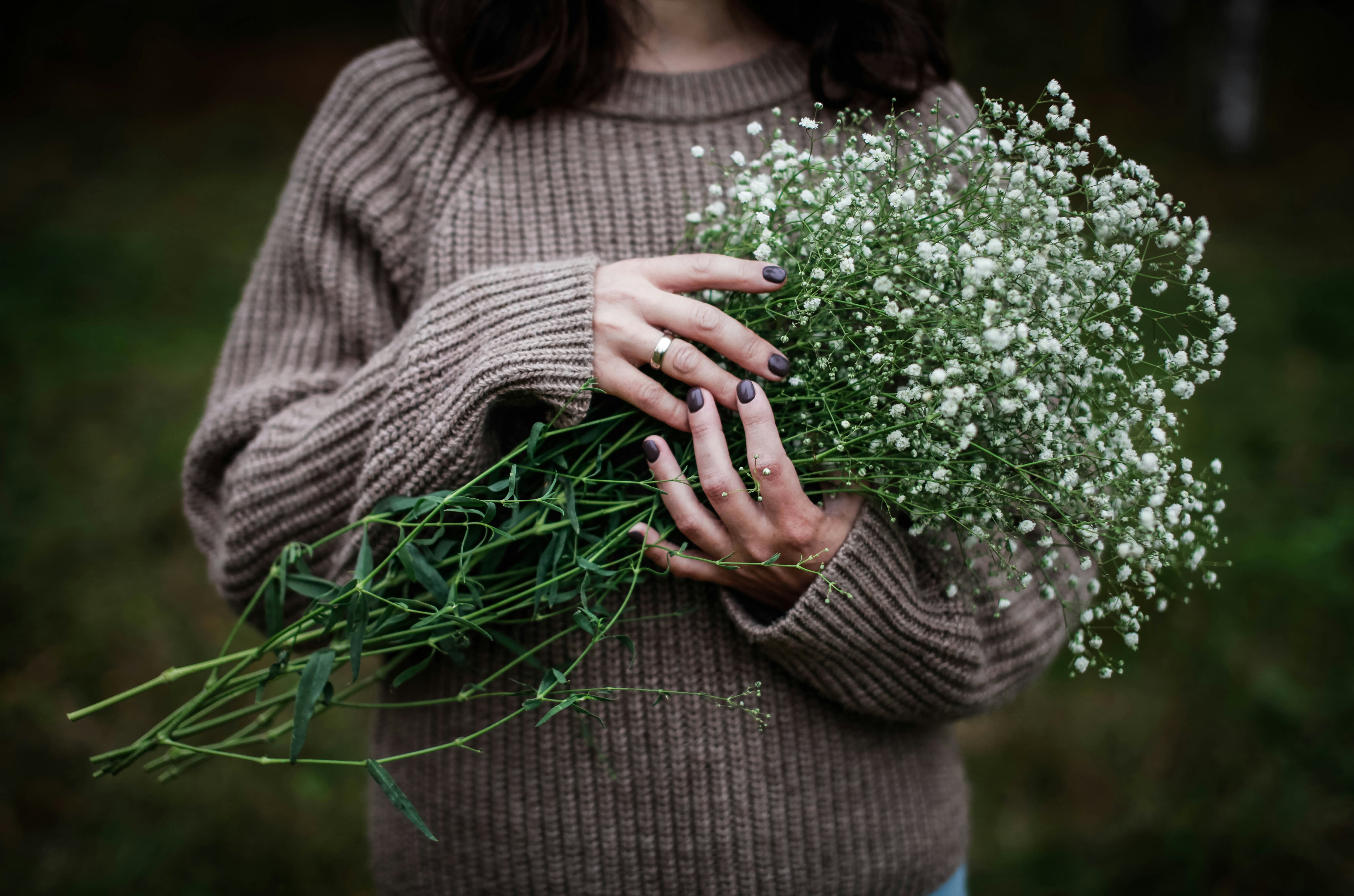 a woman holding a bunch of flowers in her hands