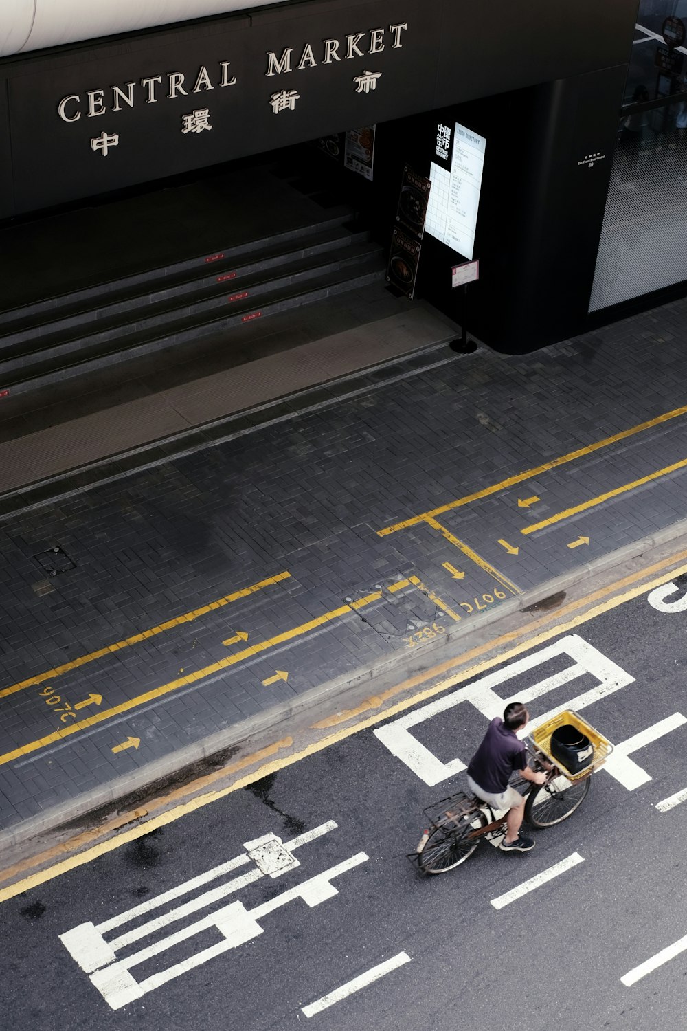 a man riding a bike down a street next to a tall building