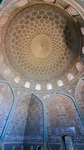 A serene blue mosque dome with golden geometric patterns glowing under soft daylight.