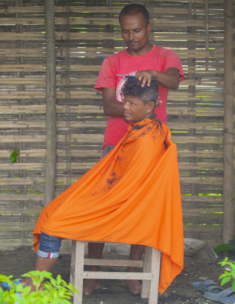 a man cutting another man's hair outside