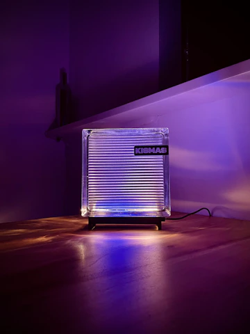 Close-up of a glowing LED acrylic lamp with an intricate personalized design, radiating warm light on a wooden table.