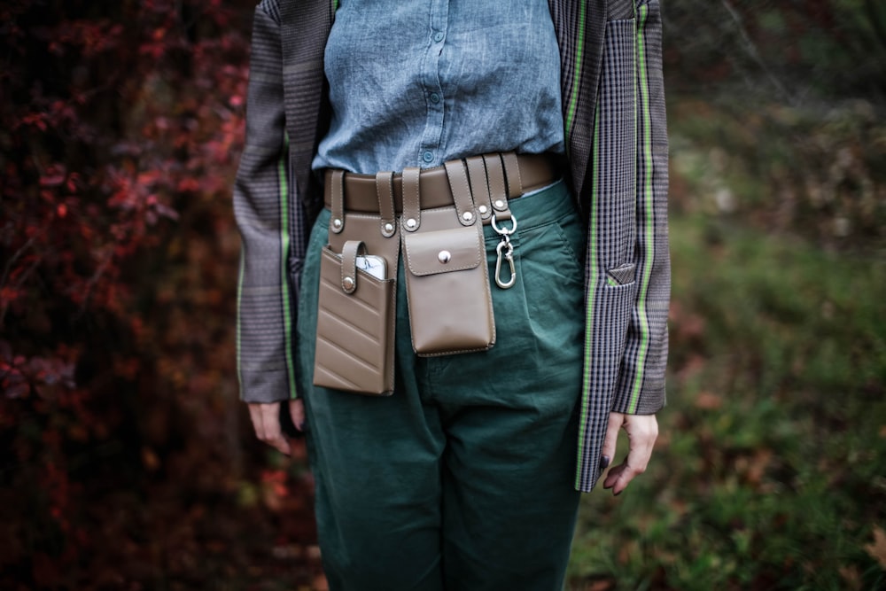 a woman wearing green pants and a brown belt