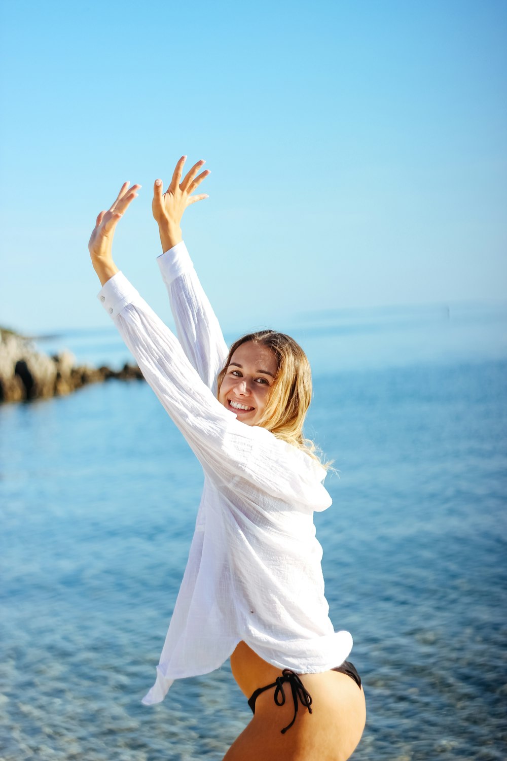 a woman in a white shirt and black shorts on the beach