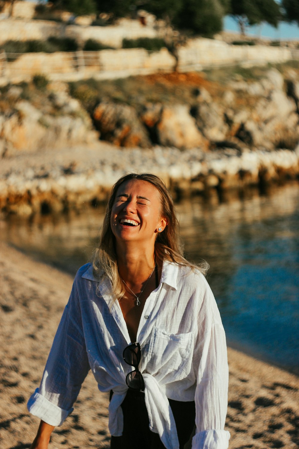 a woman walking on a beach next to a body of water