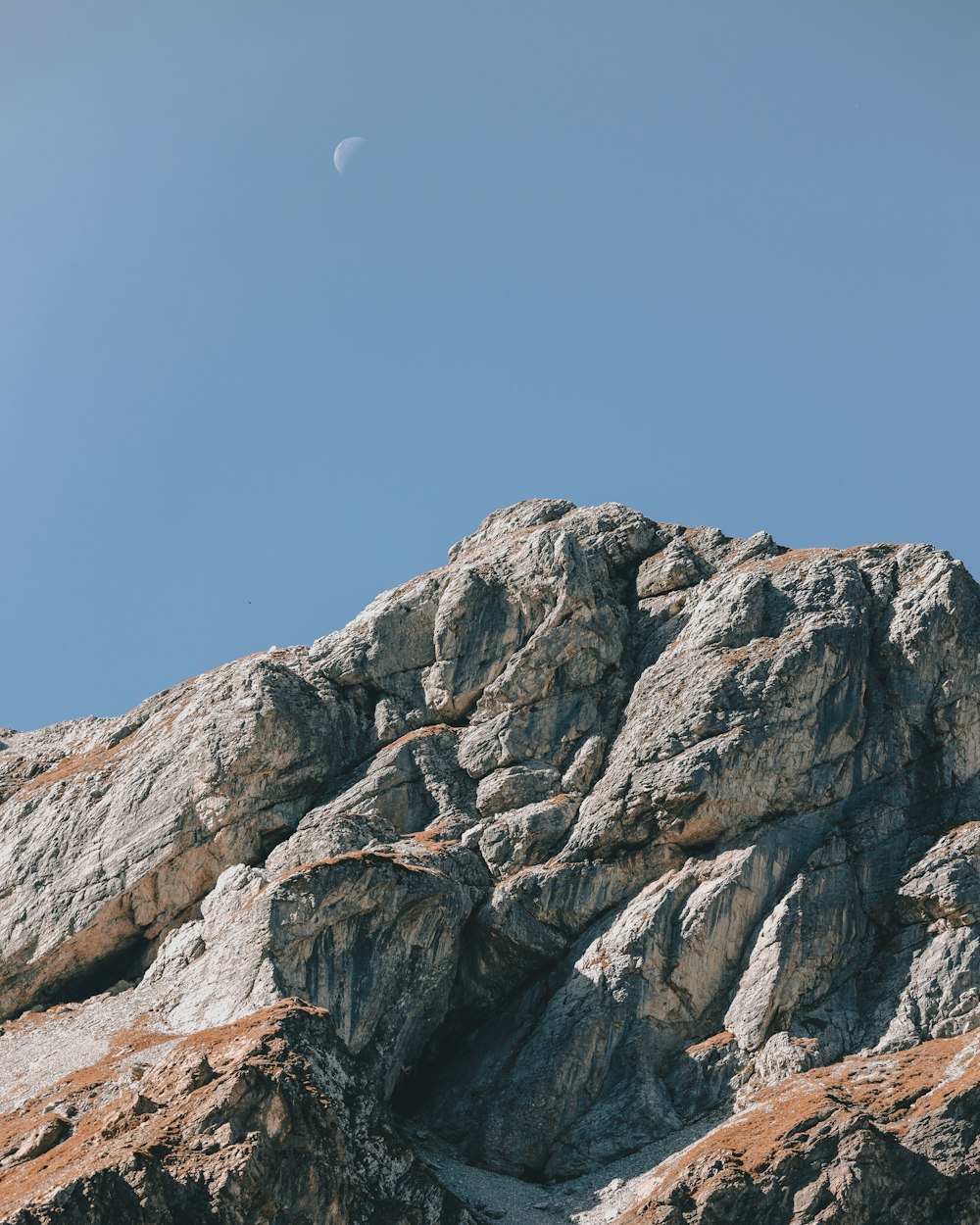 a rock formation with a half moon in the background