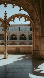 a stone building with arches and a clock tower in the background