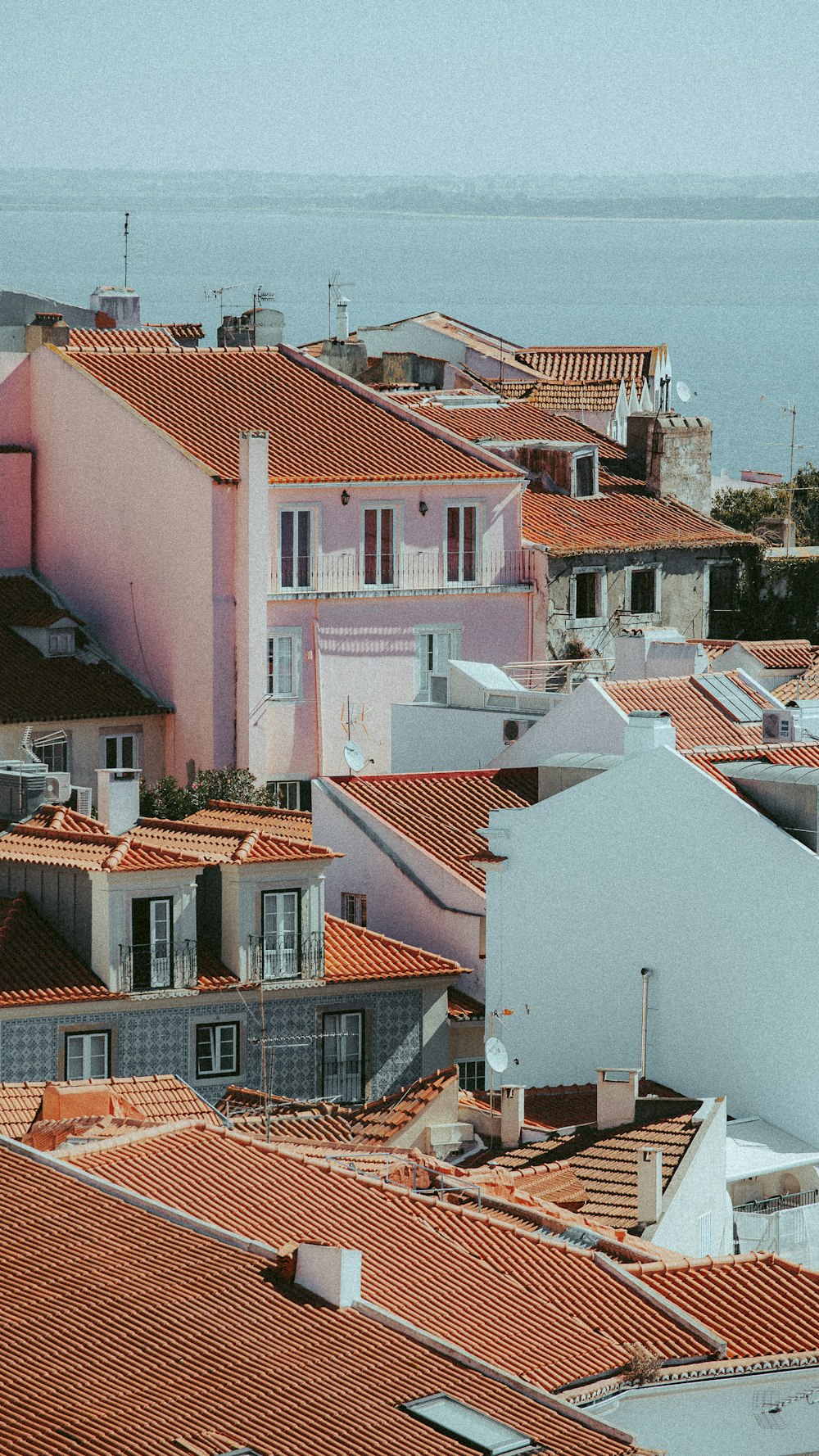 a view of a city with red roofs and a body of water in the background