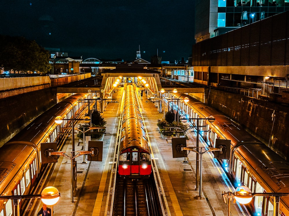 um trem vermelho viajando pelos trilhos do trem ao lado de edifícios altos