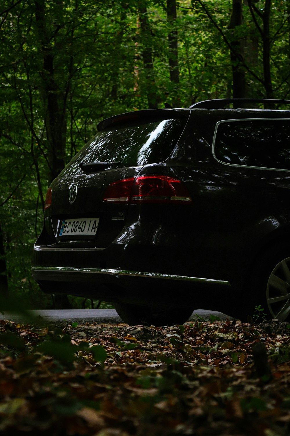 a black car is parked in the woods