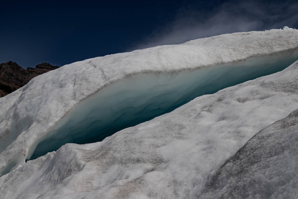 a large crack in the side of a snow covered mountain