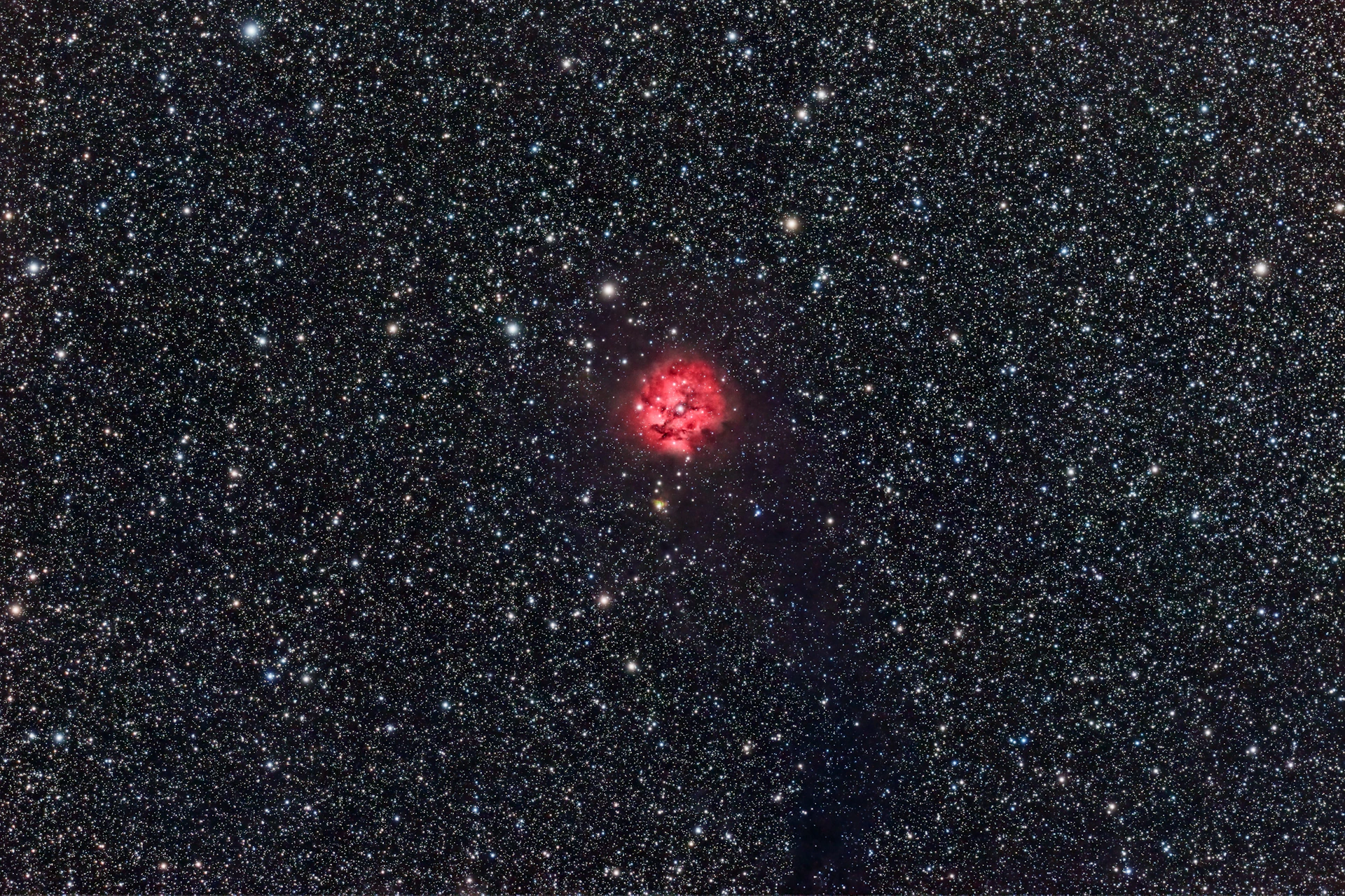 A breathtaking view of a vibrant nebula glowing in shades of red and orange, with young stars twinkling within its clouds.