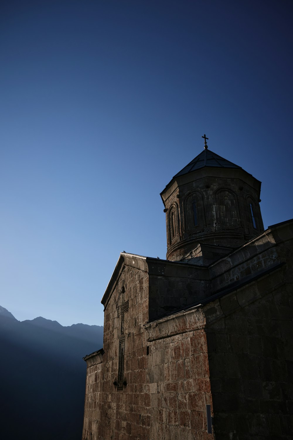 a tall brick building with a cross on top of it