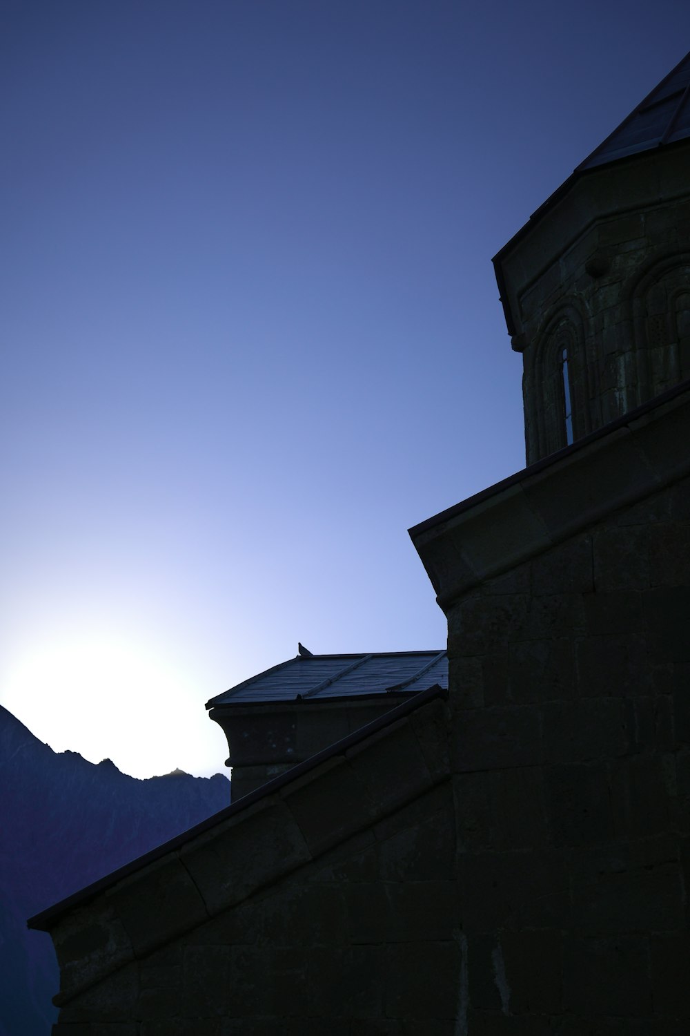 the sun is setting behind a building with a steeple