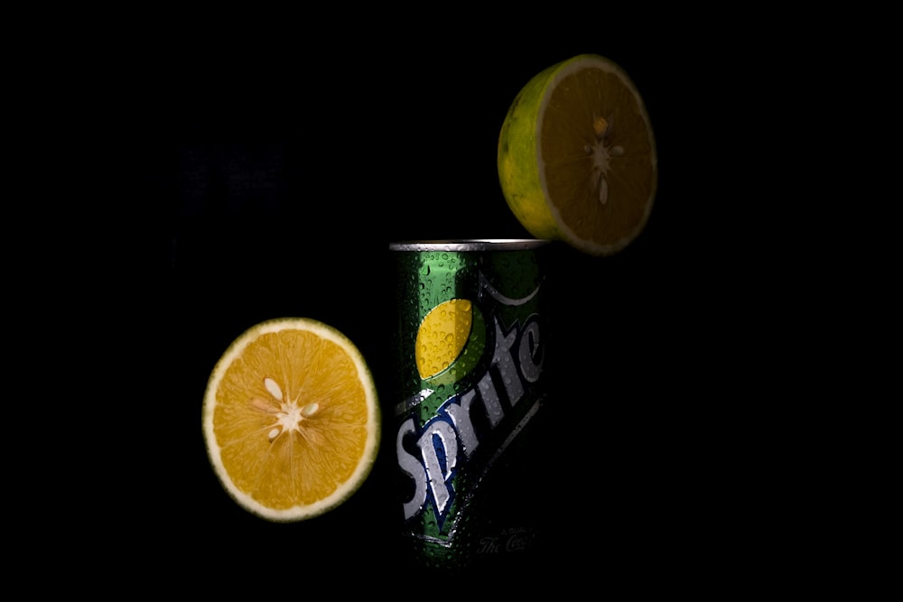two oranges and a can of soda on a black background