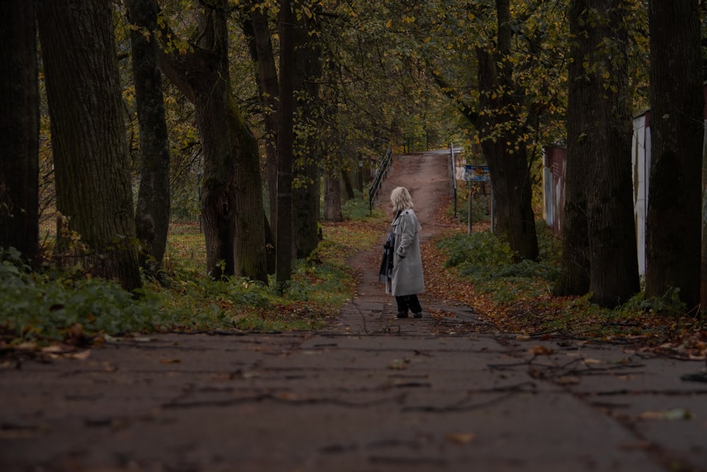 a woman is walking down a path in the woods