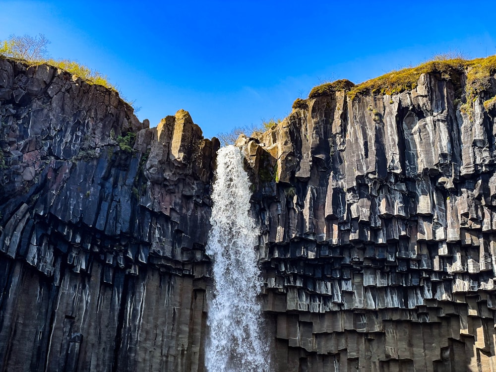 a very tall waterfall next to a large cliff