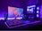A gaming setup with a monitor displaying a colorful 'Republic of Gamers' logo, accompanied by a mechanical keyboard and a gaming mouse on a desk illuminated with RGB lighting. The computer tower is visible, featuring internal cooling fans lit with vibrant blue and purple LED lights.