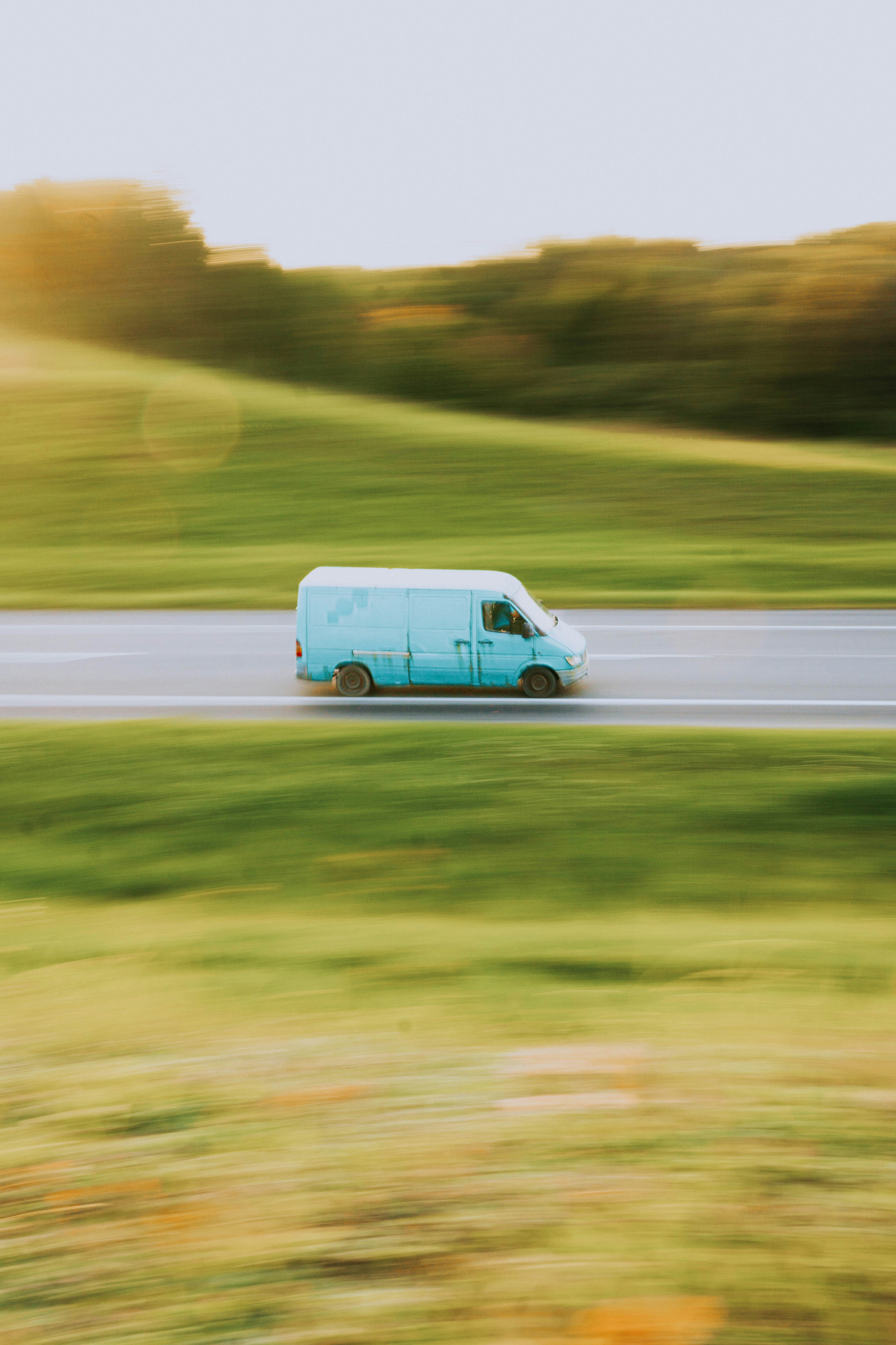 a blue van driving down the highway at sunset