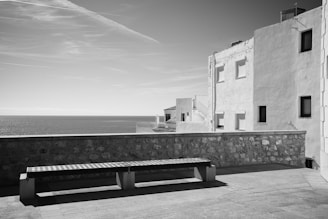 Monochrome image of a private villa terrace with minimalist furniture and soft shadows.
