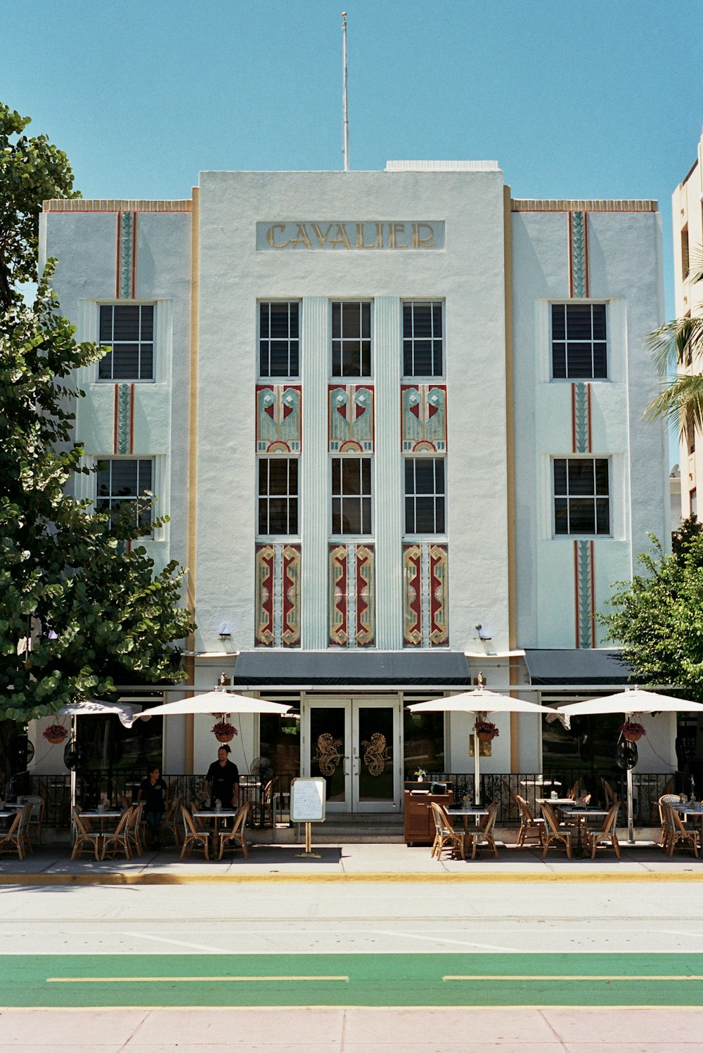 a large white building with tables and umbrellas in front of it