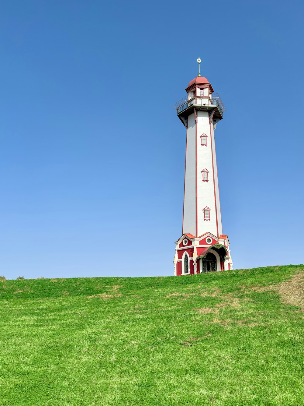 a white and red lighthouse on top of a green hill