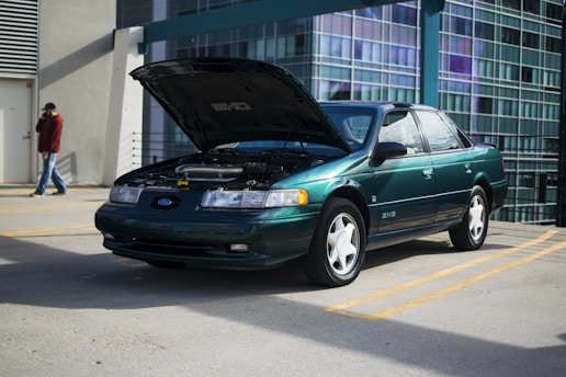 Friendly customer service representative talking on the phone with a car in the background.
