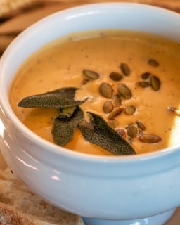 a white bowl filled with soup next to a slice of bread