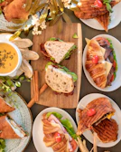 A selection of sandwiches and pan pizza on elegant plates, highlighting the café’s savory options.