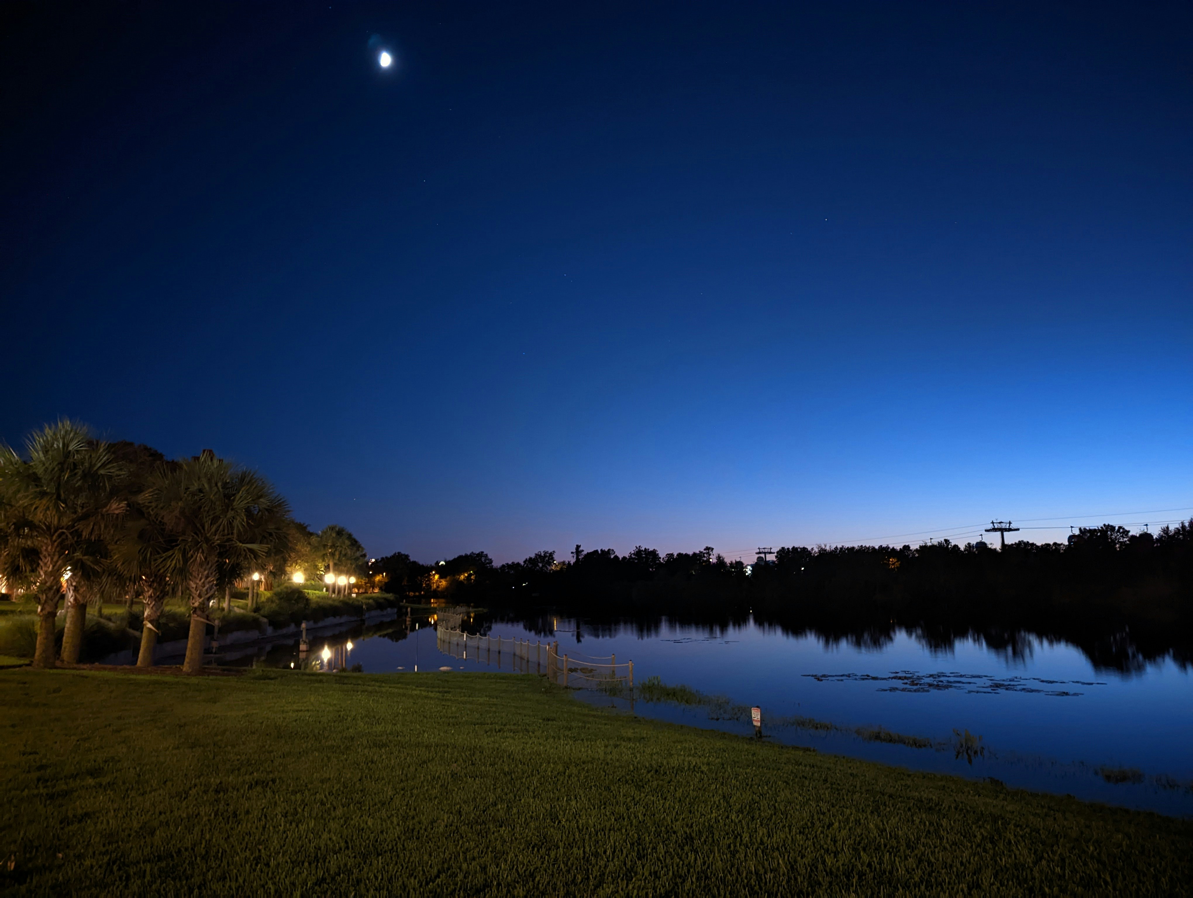 Dark night sky crescent moon reflection on still water, deep indigo shadows, atmospheric dim light