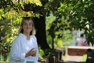 Lifestyle shot of a person enjoying a saffron-infused wellness shot outdoors with sunlight filtering through leaves