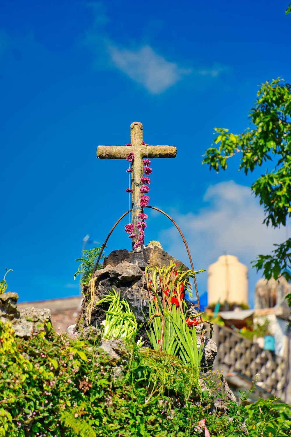 a cross on top of a rock surrounded by plants