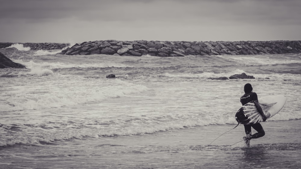 a person holding a surfboard walking into the ocean