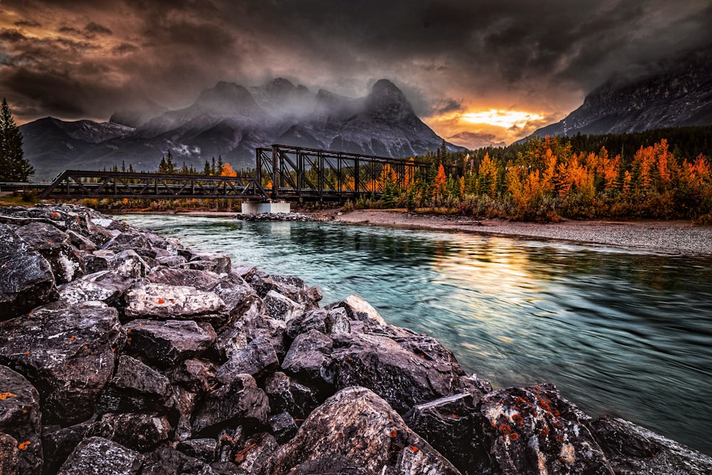 a bridge over a river with a mountain range in the background