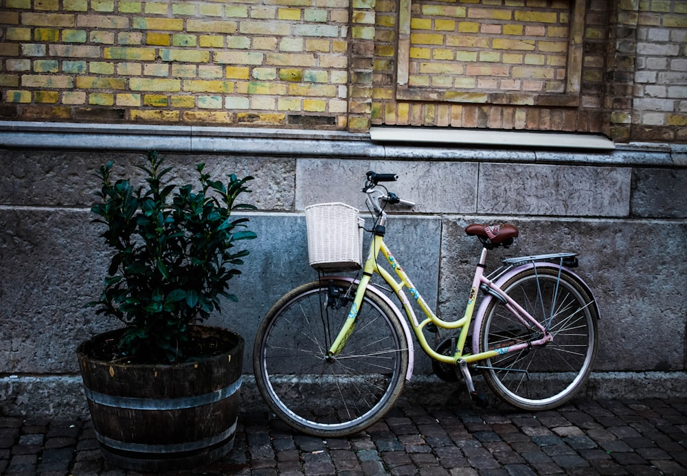 a bicycle parked next to a plant on a brick sidewalk