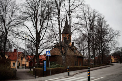 a small church with a steeple on a street corner