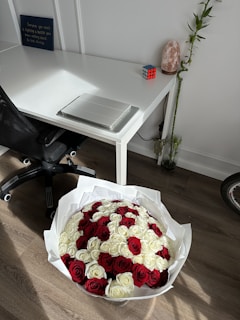 Elegant office desk with a sleek laptop and a vase of fresh flowers, reflecting a luxurious and professional atmosphere.