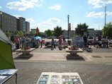A lively market scene with families enjoying the coastal vibe and handmade gifts under a bright blue sky.