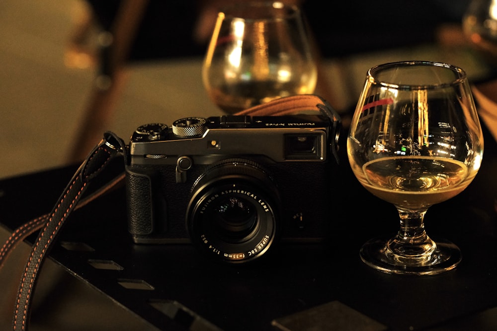 a camera and a glass of wine on a table
