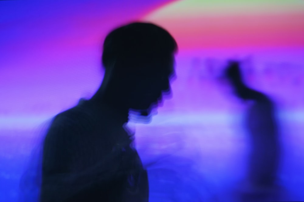 a blurry image of two people standing in front of a colorful background