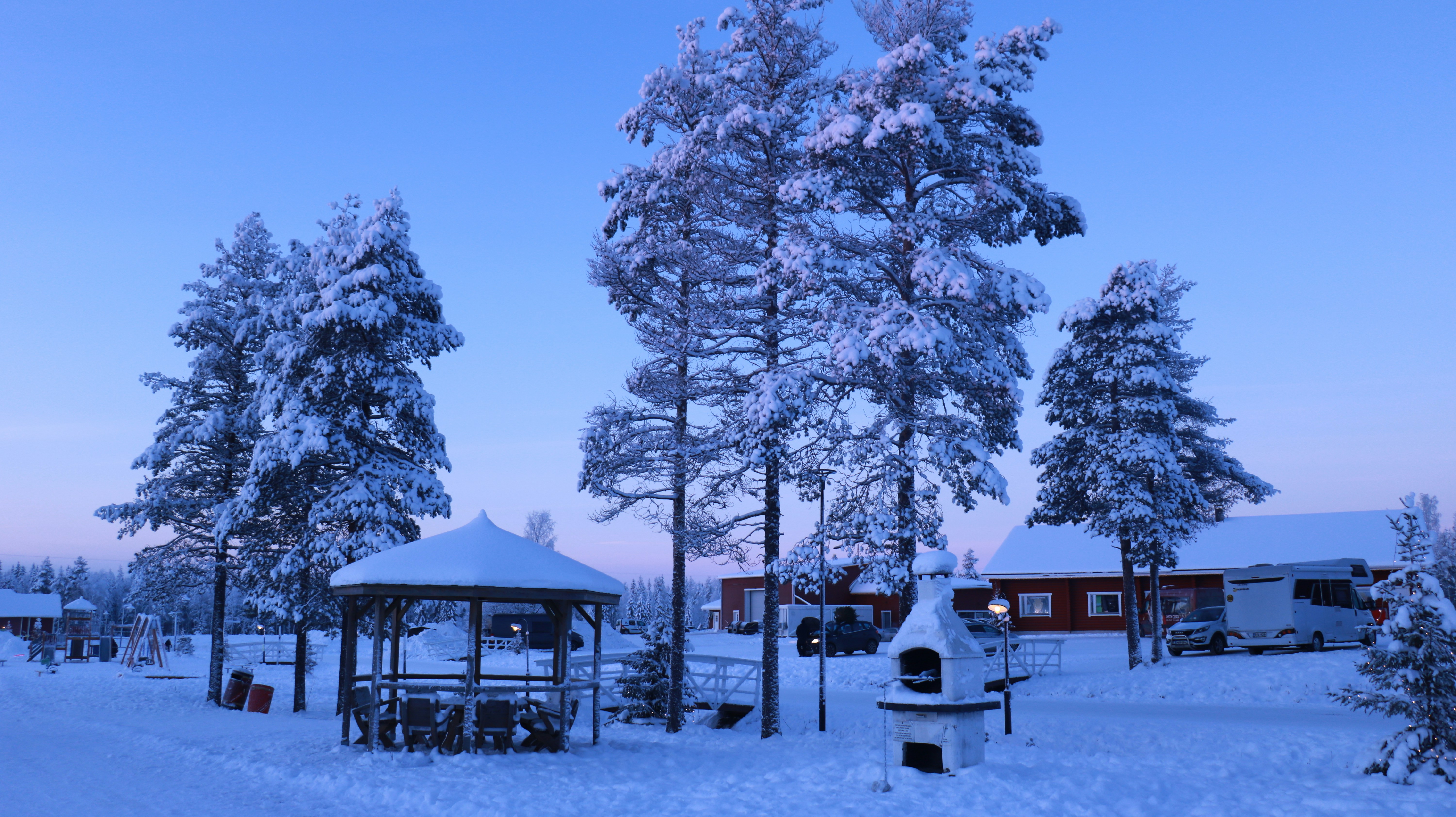 ein schneebedeckter Park mit einem Pavillon und Bäumen