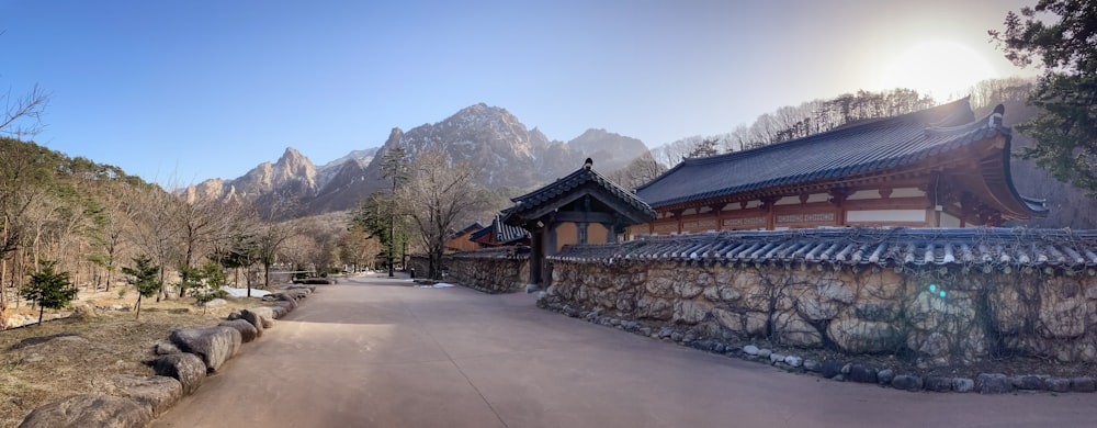 a stone wall next to a road near mountains