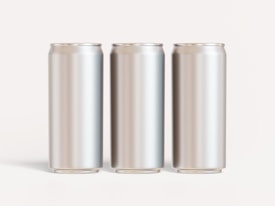 Three blank, metallic cans are arranged in a straight line against a neutral background. The cans are evenly spaced and have a shiny, reflective surface.