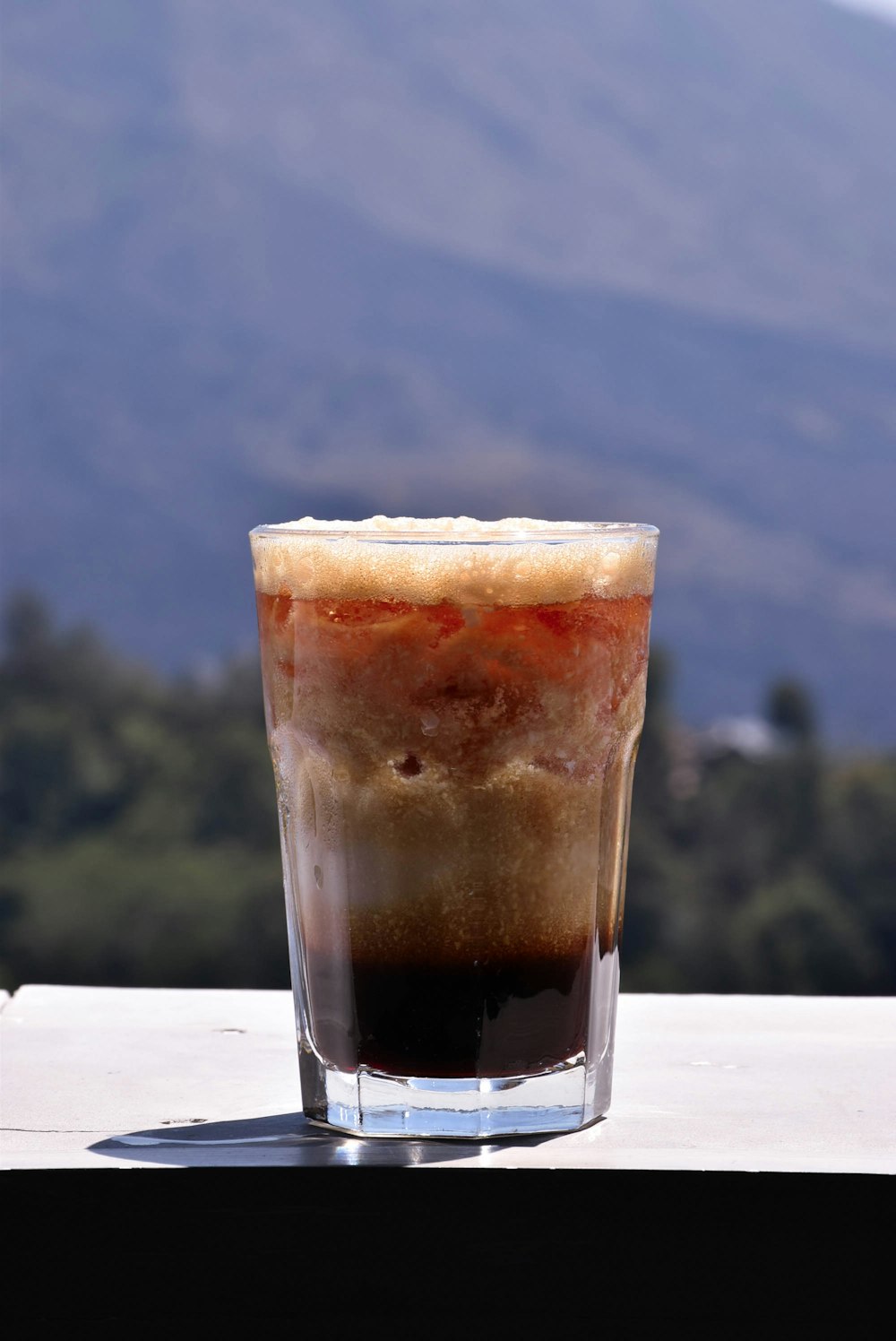 a drink sitting on top of a table next to a mountain
