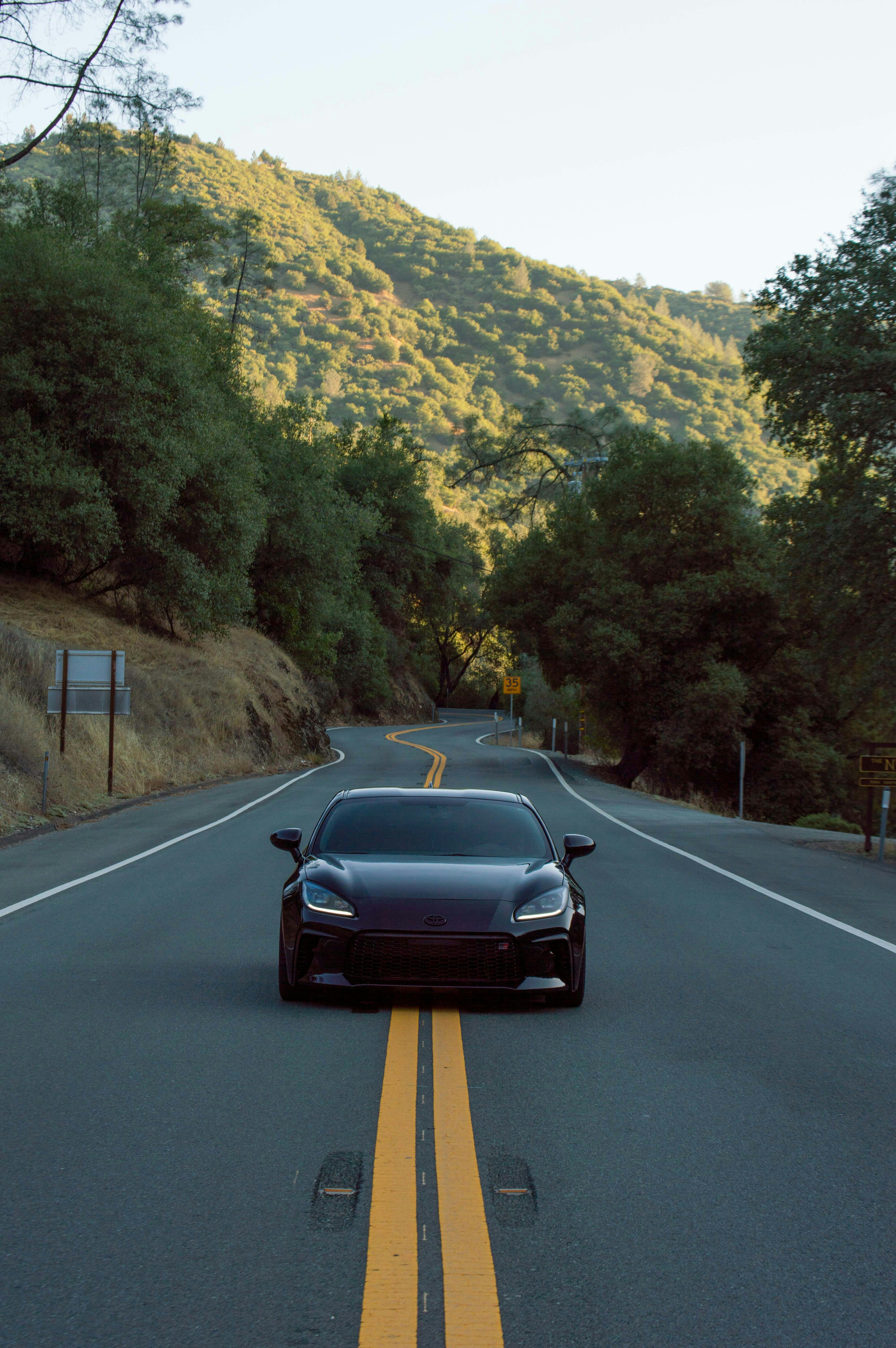 a car driving down a road with a mountain in the background