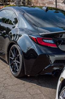Side profile of a BMW with a custom performance exhaust, parked on a dark asphalt surface with reflections.