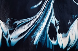 Abstract painting featuring fluid brushstrokes in shades of blue and white blending together over a dark background. The swirling patterns create a sense of movement and flow.
