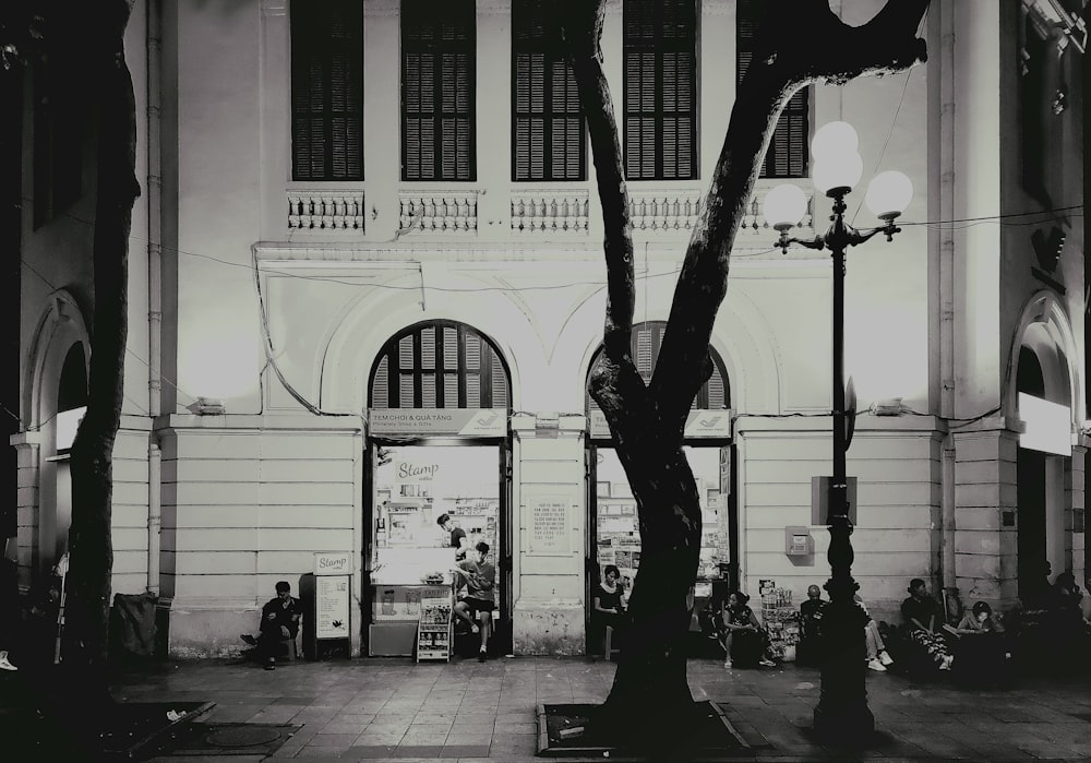 a black and white photo of a tree in front of a building