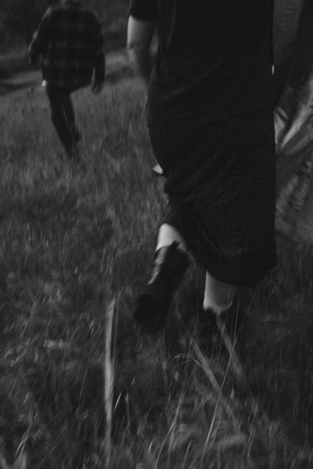 a black and white photo of two people walking in a field
