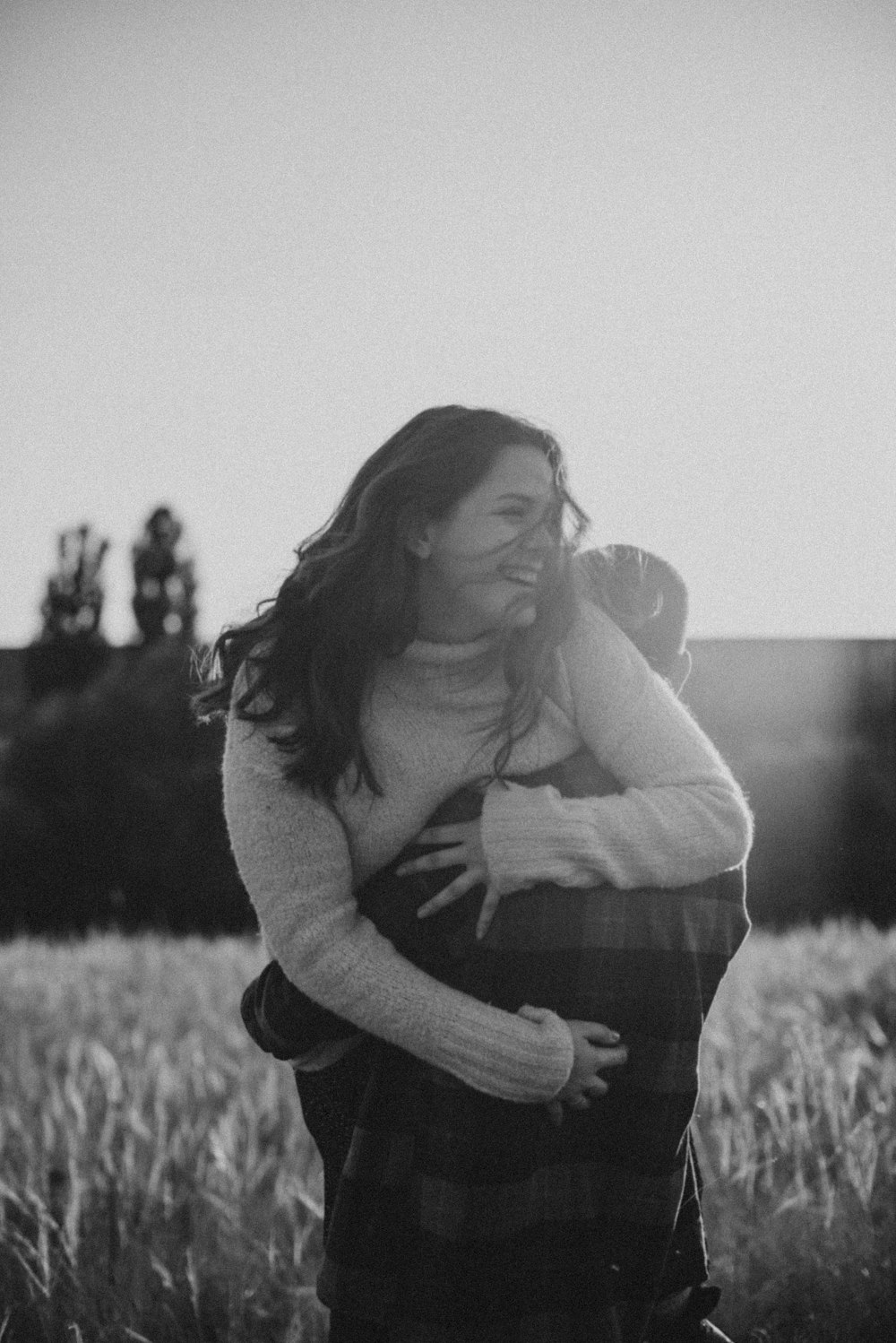 a woman hugging a man in a field of tall grass